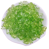 A pile of bright green acrylic bow beads for jewelry making arranged on a white dish.