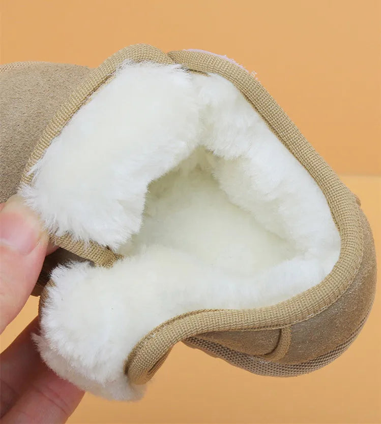 A hand holds a tan leather winter boot with a thick white faux fur lining.