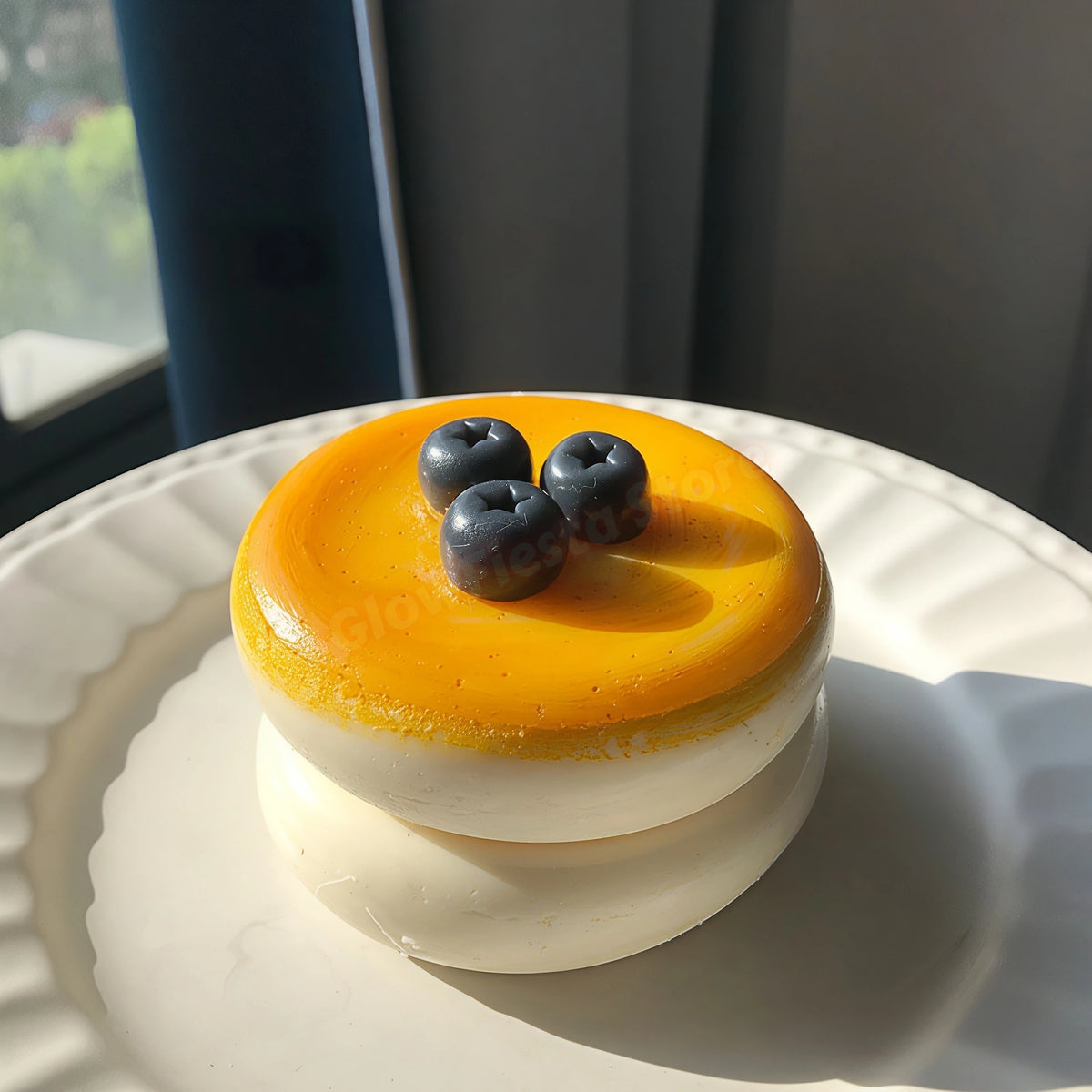 A round, layered dessert featuring a yellow soufflé top and white cream base, garnished with blueberries.