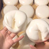 A hand is squeezing a white yogurt cake squishy stress relief toy.