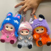 Three plush toys with pink, blue, and orange fur and faces hanging on a wall.