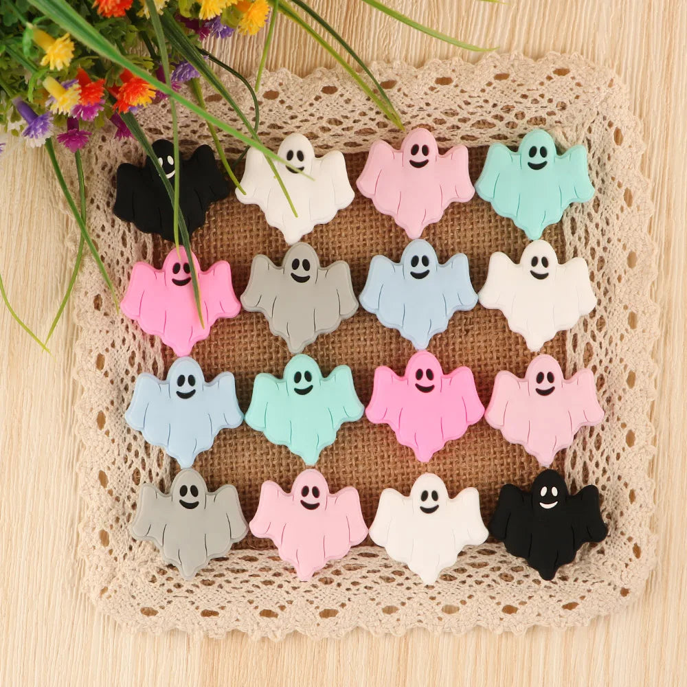 A set of five pink, white, and blue ghost silicone beads for jewelry making displayed on a woven mat.
