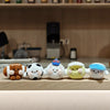 A line of cute, round plush ball keychains in various colors and textures arranged on a wooden surface.