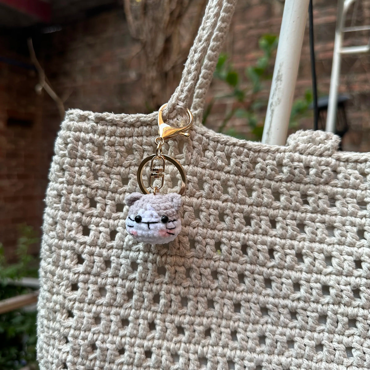 A handcrafted crochet animal keychain featuring a small, fluffy rabbit or chick charm attached to a gold-toned ring.