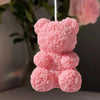 A pink 3D rose bear silicone mold for candle making hanging by a white string.