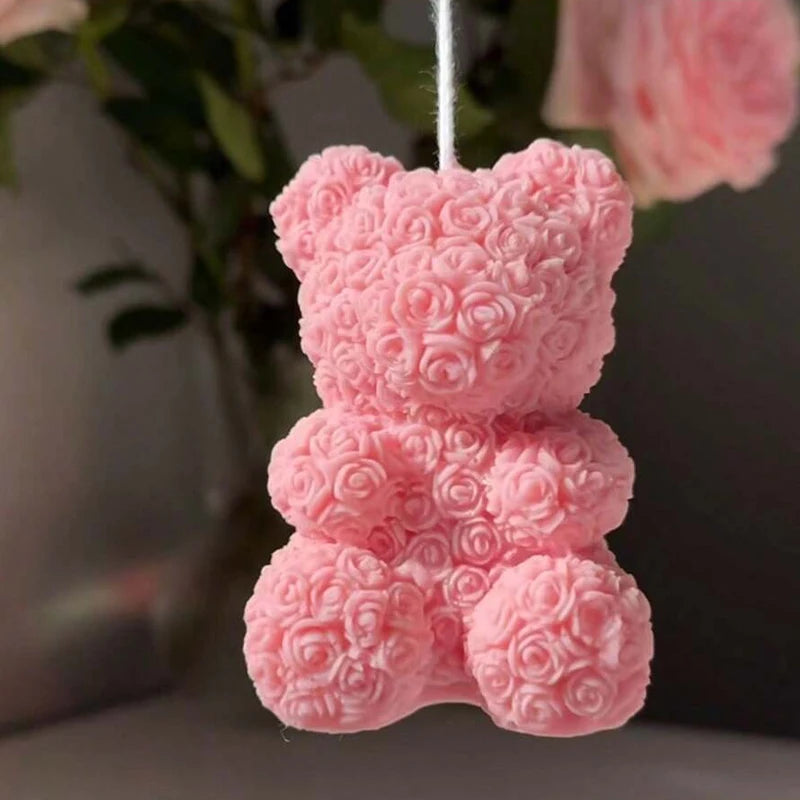 A pink 3D rose bear silicone mold for candle making hanging by a white string.