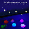 A set of colorful, luminous, floating vinyl animal toys glowing under blue light in a bathtub.