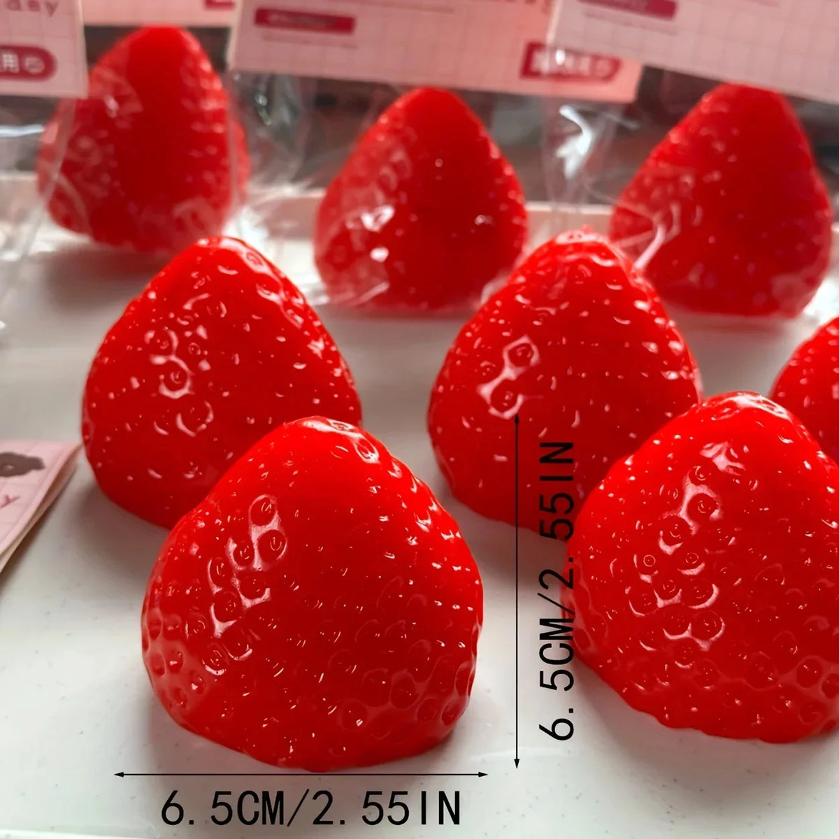 A close-up view of several bright red strawberry squishy fidget toys arranged on a white surface.