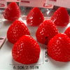A close-up view of several bright red strawberry squishy fidget toys arranged on a white surface.