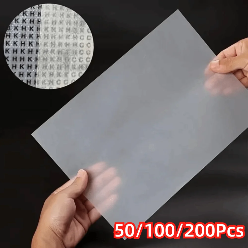 A hand holds a sheet of double-sided diamond painting release paper with a circular pattern visible on the top layer.