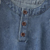 A close-up of a denim dress for a toddler girl featuring a collar and three round buttons down the front.
