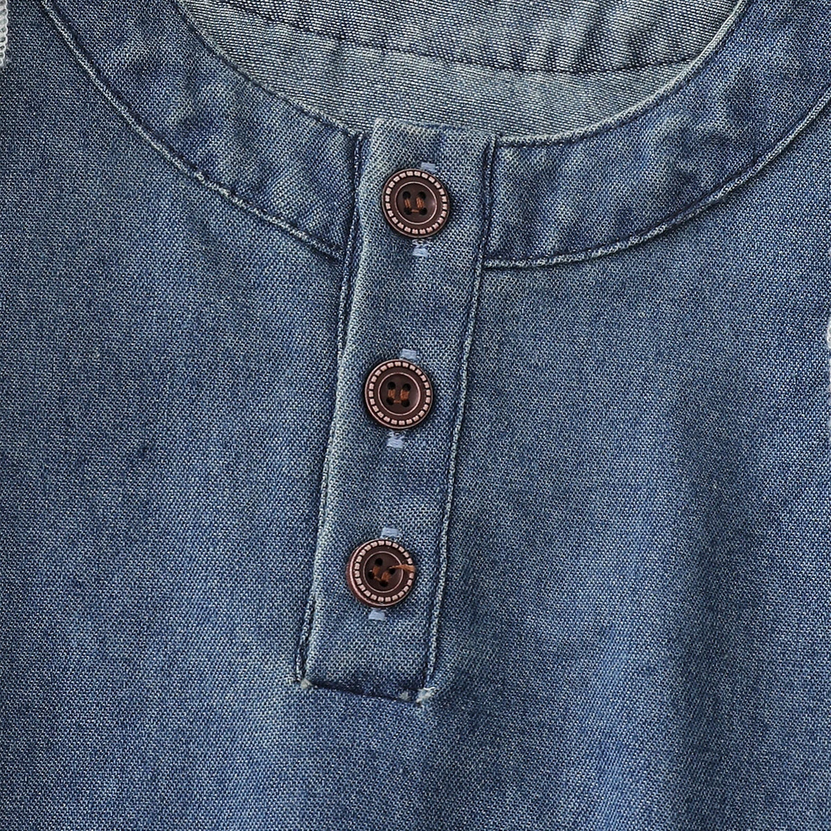 A close-up of a denim dress for a toddler girl featuring a collar and three round buttons down the front.