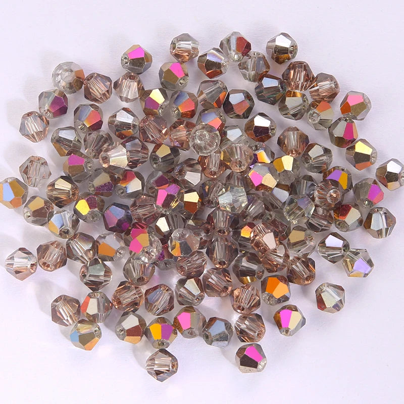 A pile of small, faceted crystal bicone glass beads in various shades of amber and pink-gold.