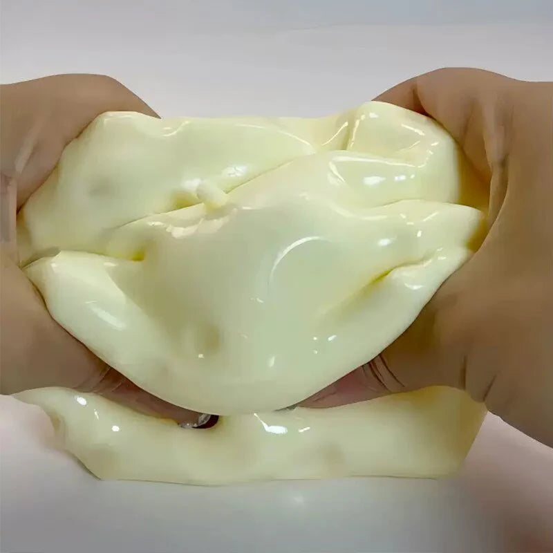 A pale yellow squishy cheese cube stress ball being held in a person's hand.