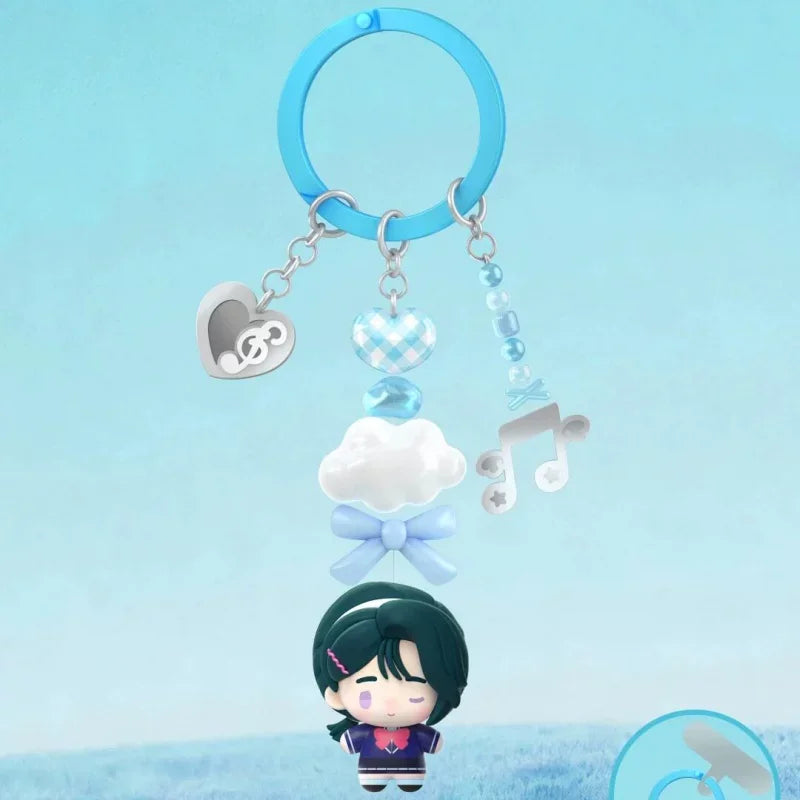 A blind box figure of a character with dark hair and purple clothing is suspended by a light blue hoop and charms against a l