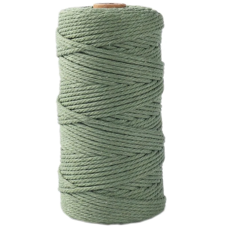 A spool of natural cotton macrame rope in a muted sage green color.
