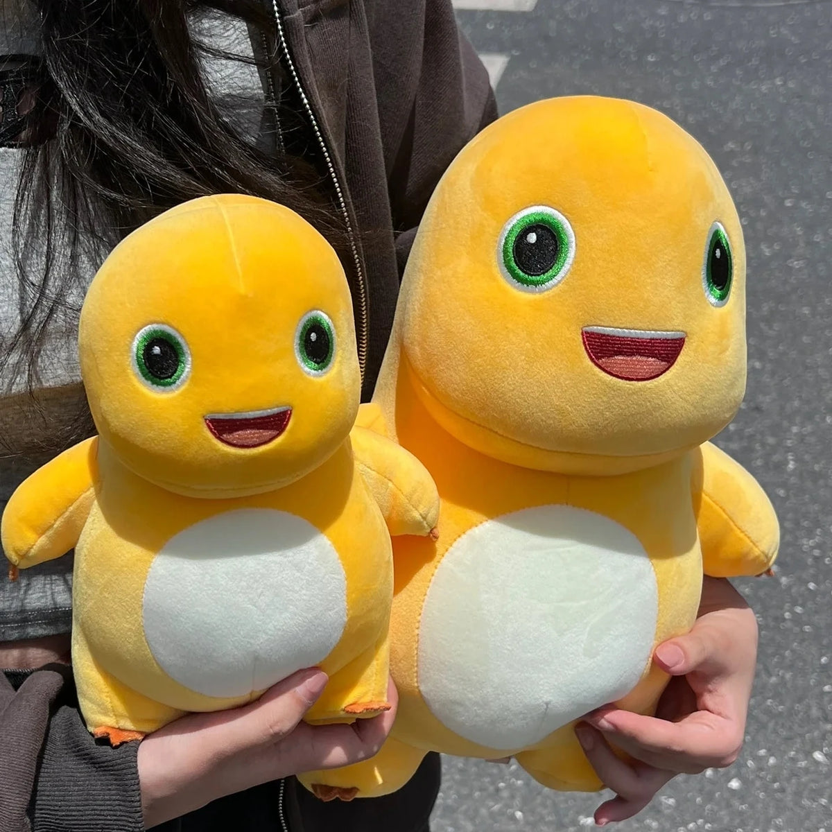 Two yellow Kawaii Milk Dragon plush stuffed animals being held by hands.
