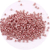 A pile of small, rose gold metallic glass beads for jewelry making.