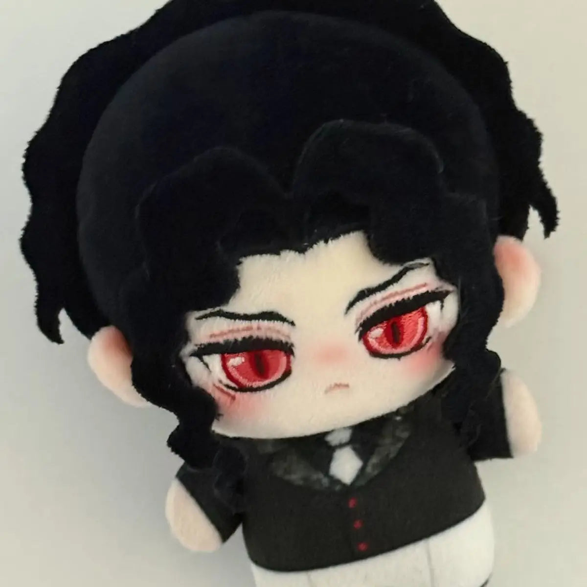 A black and white anime plush doll with dark hair and red eyes.
