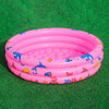 A pink inflatable kids play pool with a cartoon fish and sea creature design resting on green turf.