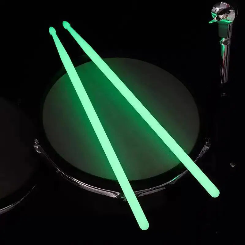 A pair of bright green glow-in-the-dark nylon drumsticks are displayed against a dark background.