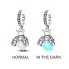 Sterling silver charm beads shaped like bees shown in normal light and in the dark.