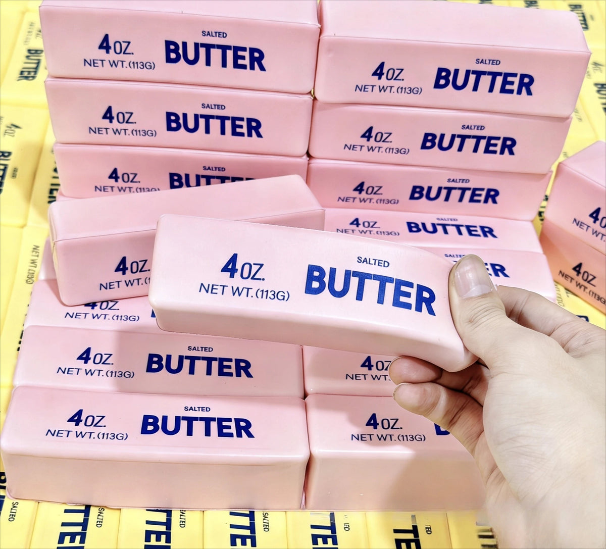 A collection of pink butter squishy blocks with blue lettering arranged in rows.