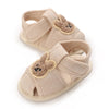 Pair of light beige soft sole sandals for baby's first steps featuring cute bear appliqués