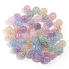 A collection of round loose glitter cracked acrylic beads in various shades of purple, pink, and green.