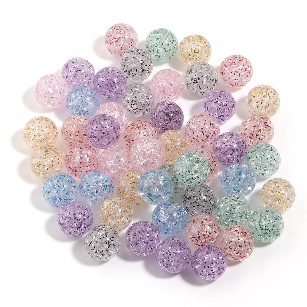 A collection of round loose glitter cracked acrylic beads in various shades of purple, pink, and green.
