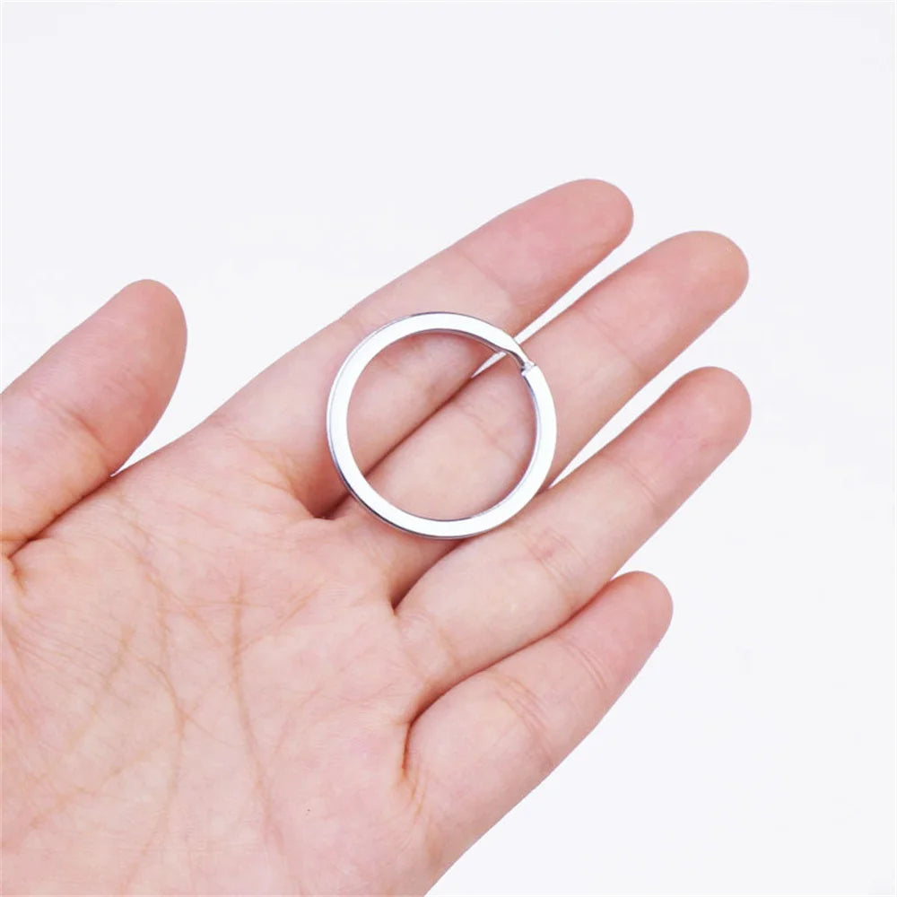 A hand holds a silver metal keychain hook with a swivel clasp and key ring.
