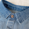 Close-up of a blue and white striped denim shirt with a collar and button detail.