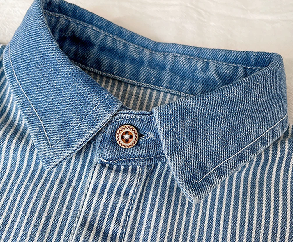 Close-up of a blue and white striped denim shirt with a collar and button detail.