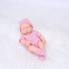 A realistic soft vinyl baby doll wearing a pink striped outfit and matching hat, lying on a white surface.
