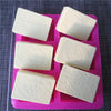 Six square silicone molds with floral patterns for DIY soap making arranged in a pink tray.
