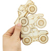 A hand holds a set of unfinished wood monster truck cutouts for DIY crafts.