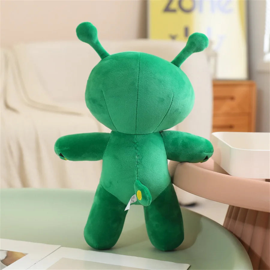 An adorable green alien plush toy with long ears sitting on a light green surface.