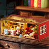 A wooden miniature dollhouse kit featuring a detailed interior display of food and furniture.