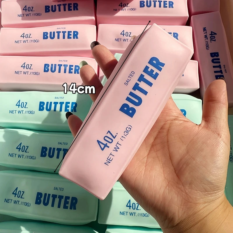 A hand holds a pink butter stick squishy fidget toy with various sized butter sticks in the background.