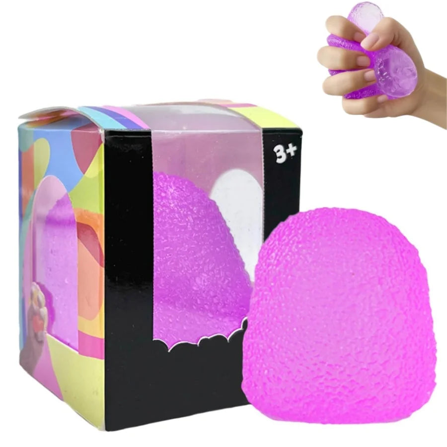 A bright pink slow rise squishy stress ball is shown next to a hand squeezing a purple version.