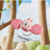 A pink, round animal toy is shown hanging from a wooden structure against a bright sky background.