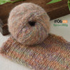 A ball of soft, fuzzy, pinkish-brown alpaca blend yarn next to a knitted scarf.