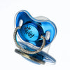 A clear blue silicone baby pacifier featuring a crown design and the name Toby spelled out in gold rhinestones.