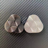 Two silver metal magnetic fidget sliders resting on a dark carbon fiber surface.