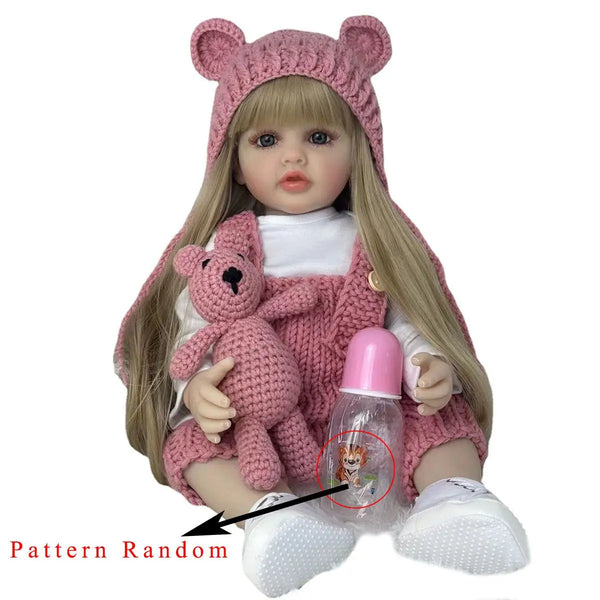 Muñeca bebé con cabello rubio largo vistiendo un gorro de punto rosa y un conjunto a juego, sosteniendo una botella pequeña.