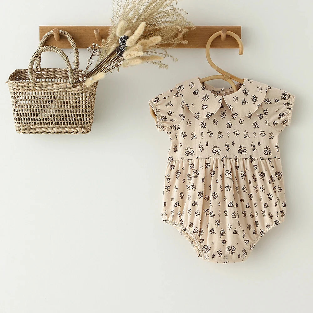 A vintage floral baby girl outfit set featuring a blouse and romper, displayed on a wooden hanger.