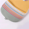 A stack of colorful silicone baby bibs with catch pockets displayed on a light gray dish.