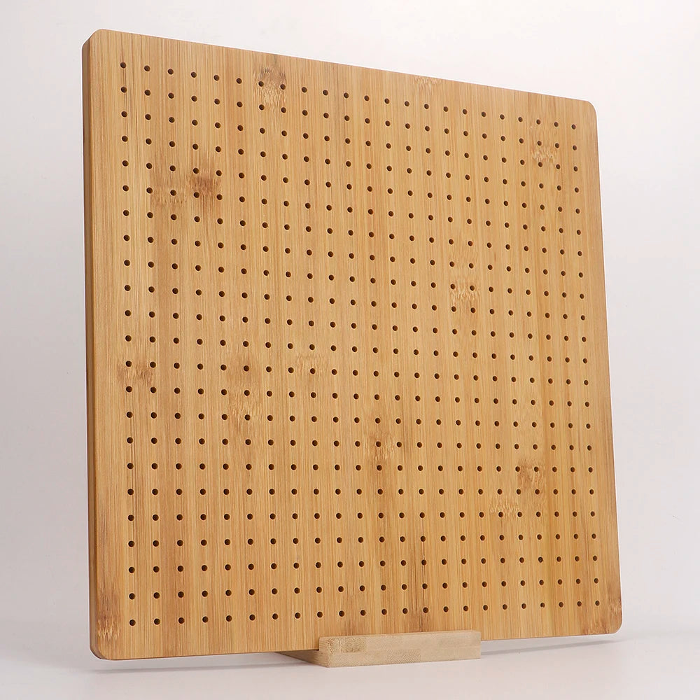 A light wood bamboo crochet blocking board with numerous small pins and a stand.