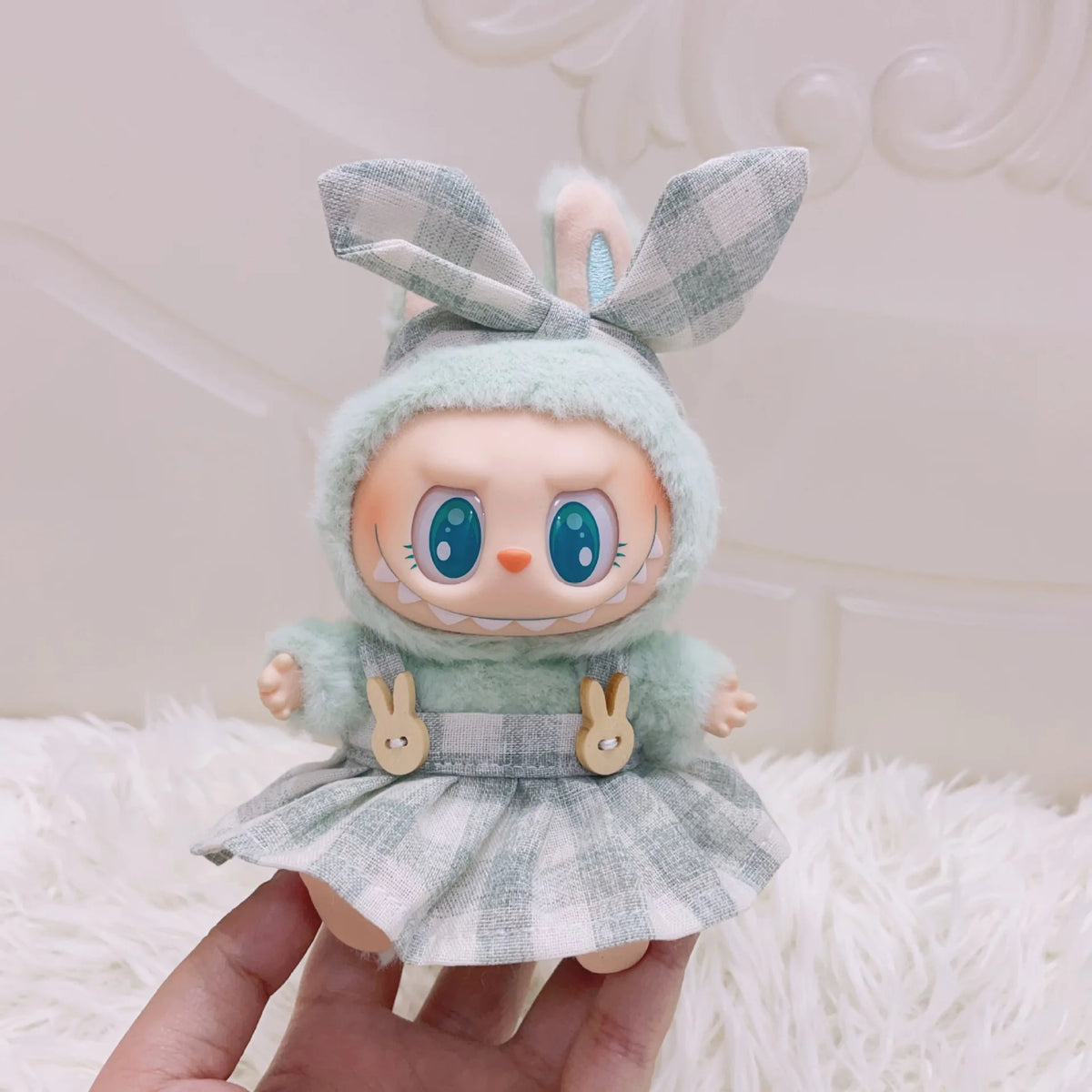 A cute doll wearing a light green outfit and a plaid dress with bunny ears