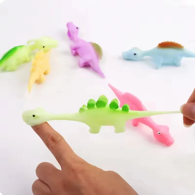 A set of five colorful rubber dinosaur slingshot toys, including green, yellow, purple, blue, and pink.